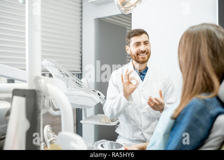 Beau dentiste talking with woman patient pendant la consultation médicale en cabinet dentaire Banque D'Images