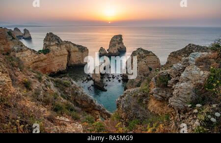 Le lever du soleil sur la mer, côte rocheuses de grès, formations rocheuses dans la mer, Ponta da Piedade, Algarve, Lagos, Portugal Banque D'Images