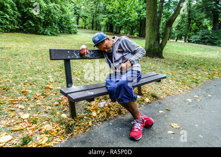 Un vieil homme sur un banc dans un parc solitude, un sans-abri dans un parc urbain un homme âgé fatigué Banque D'Images