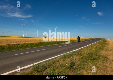 Un motocycliste dans un paysage agricole avec les éoliennes dans l'arrière-plan Banque D'Images