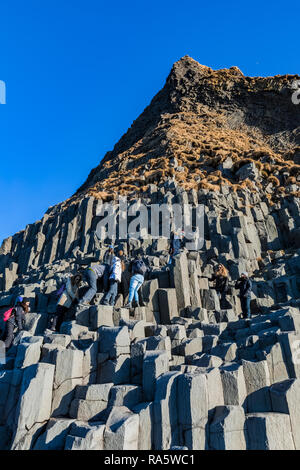 Les touristes grimper sur les formations des orgues basaltiques le long de la plage de sable noir de Reynisfjara qui jouit en Islande Banque D'Images