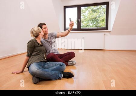 Jeune couple photographing themselves dans un nouvel appartement Banque D'Images