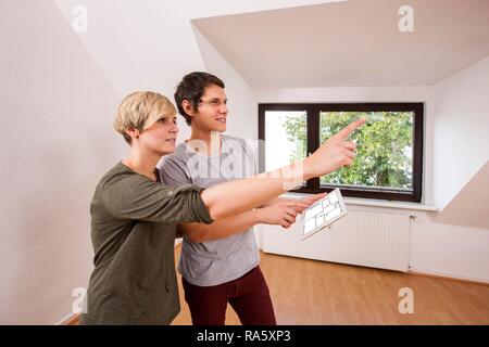 Jeune couple dans un nouvel appartement, la planification de l'ameublement avec l'aide d'un iPad Banque D'Images