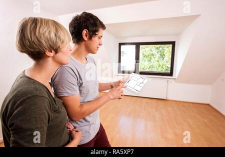 Jeune couple dans un nouvel appartement, la planification de l'ameublement avec l'aide d'un iPad Banque D'Images