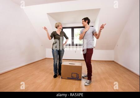 Jeune couple transportant le premier déménagement fort dans le salon vide dans un nouvel appartement Banque D'Images