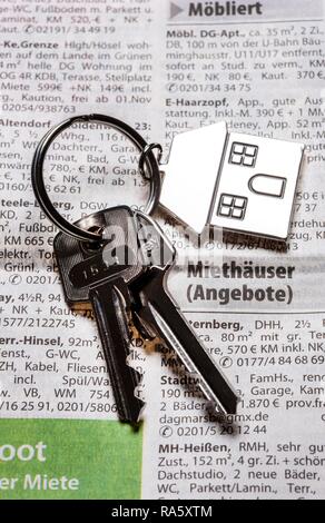 Deux clés avec une clé en métal en forme de tag comme une maison se trouvant sur la page de l'immobilier d'un quotidien, image symbolique pour l'accueil Banque D'Images