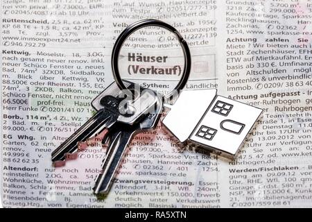 Deux clés avec une clé en métal en forme de tag comme une maison se trouvant sur la page de l'immobilier d'un quotidien allemand Banque D'Images
