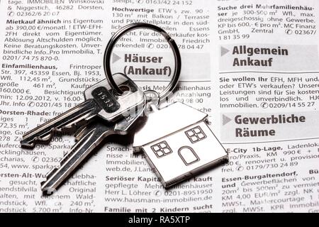 Deux clés avec une clé en métal en forme de tag comme une maison se trouvant sur la page de l'immobilier d'un quotidien allemand Banque D'Images