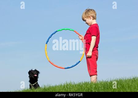 La formation de chien, garçon encourageant un chien de sauter à travers un cerceau, Wilhelmsburg, Hambourg, Hambourg, Allemagne Banque D'Images