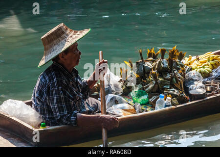 Damnoen Saduak - 4 mars 2014 : une femme vendeur paddles son bateau le long du canal. La ville est célèbre pour son marché flottant. Banque D'Images