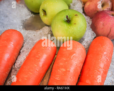 Les carottes, les pommes, les pommes vertes sur la glace de fruits qui sont vendus sur le marché Banque D'Images