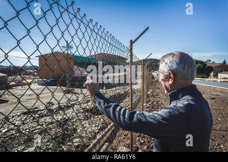 Un homme âgé à la clôture intermédiaire avec fond de ciel bleu Banque D'Images