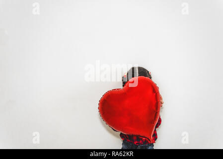 Jolie petite fille adorable se cache derrière un ballon en forme de coeur rouge soumission.Concept image avec fond isolé