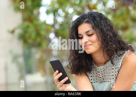 Smiley girl smart phone content dans le parc avec un fond vert Banque D'Images