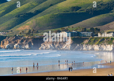 Jan 2017 Pismo State Beach CA : vert avec des collines et falaises de couleur de craie dans l'arrière-plan les gens à pied près de bord de l'eau de la plage. Banque D'Images