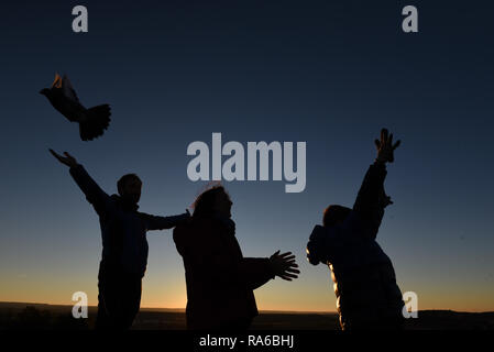 Silhouette de personnes vu libérer les pigeons voyageurs d'accueillir l'arrivée de la nouvelle année au coucher du soleil à Almazán, au nord de l'Espagne. Banque D'Images