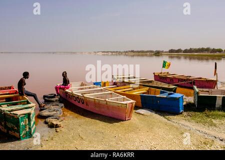 Deux jeunes femmes assises sur des bateaux en bois colorés au Lac Rose, Dakar, Sénégal région Banque D'Images