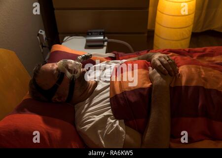 L'homme avec l'apnée du sommeil, porte un masque CPAP pendant le sommeil, masque respiratoire, qui pousse l'air dans les voies respiratoires en raison Banque D'Images