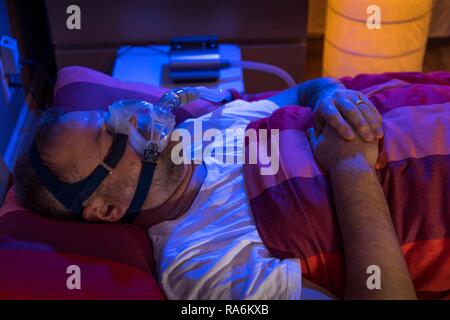 L'homme avec l'apnée du sommeil, porte un masque CPAP pendant le sommeil, masque respiratoire, qui pousse l'air dans les voies respiratoires en raison Banque D'Images