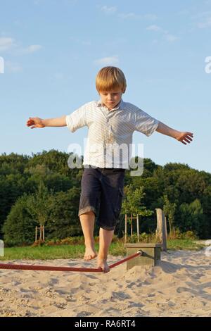 Jeune garçon en équilibre sur une corde en Egestorf Barefoot Park, Egestorf, Basse-Saxe, Allemagne Banque D'Images