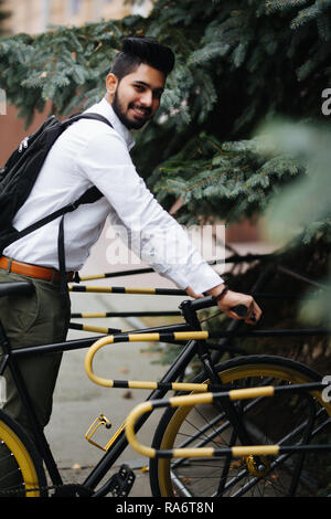 Business, mode de vie, de transport et de personnes concept - jeune homme indien location parking on city street Banque D'Images