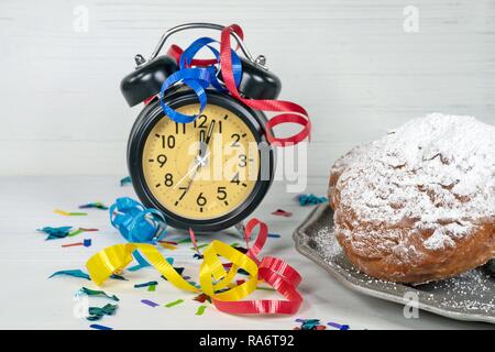 Confettis et ruban sur retro horloge avec l'heure de minuit et de nouvelles années Dutch oliebollen sur plaque d'étain Banque D'Images