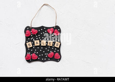 Mot de vente, jelly coeurs et étoiles décoration sucre sur un tableau noir, fond blanc, copyspace. Haut de la vue, télévision lay, immersive. Valentines Day shopping Banque D'Images