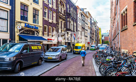 Balades touristiques adopté des vélos et des voitures en stationnement dans l'étroite Beursstraat près de Damrak, thecity centre d'Amsterdam aux Pays-Bas Banque D'Images