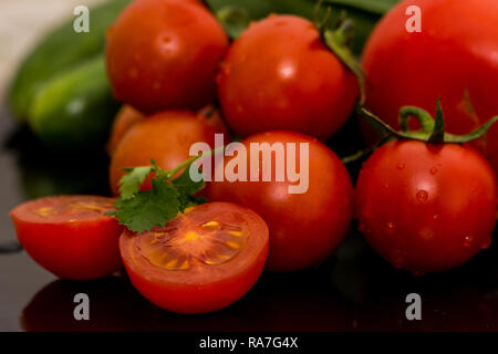 Tomates isolées, concombres et légumes au persil sur la table de cuisine prêts pour faire de la salade Banque D'Images