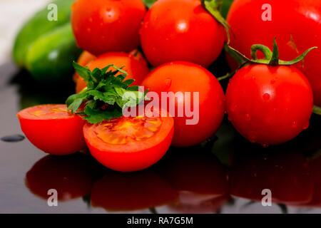 Tomates isolées, concombres et légumes au persil sur la table de cuisine prêts pour faire de la salade Banque D'Images