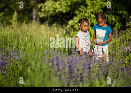 Deux jeunes sœurs traîner dans une communauté urbaine sur le jardin ensoleillé un soir d'été. Banque D'Images