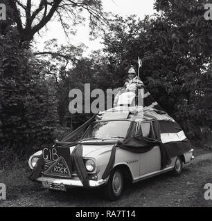 Entre 2 Lacs, 1967 Fête du village, jeune fille en robe de soirée et avec une cape Union Jack assis sur une chaise fixée sur le dessus d'une voiture décorée avec un "Rule Britannia" signe sur elle, England, UK Banque D'Images