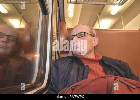 Un homme âgé dans les verres la navette au travail. L'âge moyen à l'homme par la fenêtre du train. Pendant le voyage des passagers par train express à grande vitesse Banque D'Images