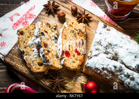 Stollen de Noël traditionnel avec ftuitcake les fruits séchés et les noix sur la table en bois sombre. La nourriture de Noël. Vue d'en haut. Banque D'Images