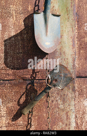 Sur le mur de métal rouillé du village faire accrocher sur les chaînes utilisées old vintage outils agricoles. Jour de printemps ensoleillé tourné Banque D'Images