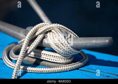 Flexible blanc amarre tressée corde à partir de voile noué sur le côté bien solide fiable support métallique de couleur argent renforcé sur le bord de bleu Banque D'Images
