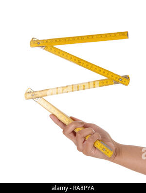 Un close up image of a hand holding a'bois jaune ruler de zollstock, un outil de charpentier, isolée pour fond blanc Banque D'Images