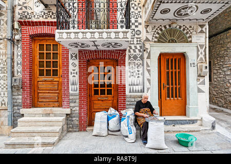 Femme de la région travaillent à l'extérieur d'une maison traditionnelle décorée de motifs géométriques le scratch dans le village médiéval de mastic de Chios, Grèce sur Pyrgi Banque D'Images