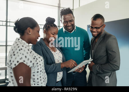 Équipe de gens d'affaires de l'Afrique debout et sourire et rire pendant l'utilisation d'une tablette Banque D'Images