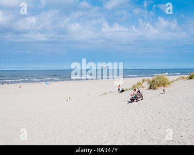 Les gens sur la plage et de la mer du Nord avec la plate-forme de forage en mer, à l'ouest de l'île de la Frise, Frise, Pays-Bas Banque D'Images