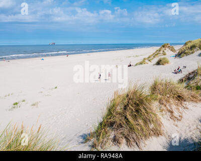 Les gens sur la plage et de la mer du Nord avec la plate-forme de forage en mer, à l'ouest de l'île de la Frise, Frise, Pays-Bas Banque D'Images