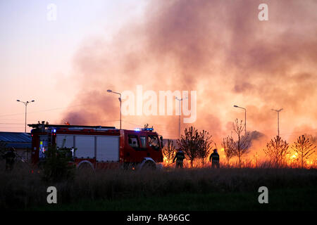 Équipe de lutte contre l'incendie Les pompiers dans la soirée. Camion à incendie sur la base des flammes et de la fumée. Banque D'Images