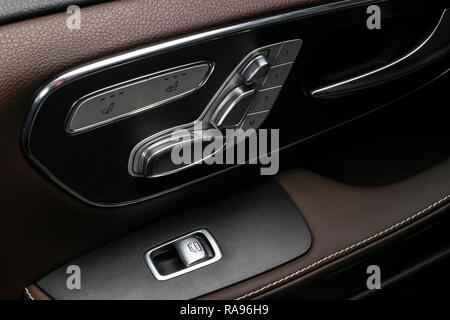 Poignée de porte avec fenêtre d'alimentation et de commande du siège de luxe boutons d'une voiture de tourisme. Intérieur en cuir perforé marron avec surpiqûres blanches du luxe Banque D'Images