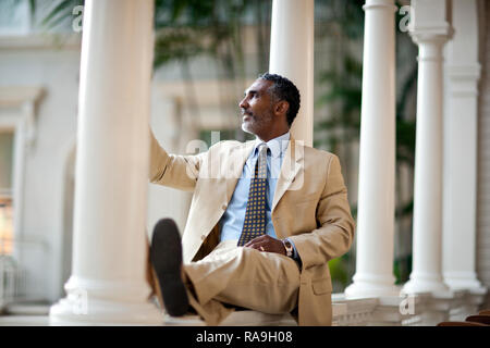 Mature businessman sitting par des piliers en face de son hôtel. Banque D'Images