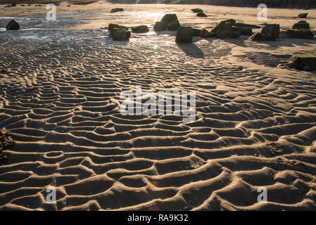 Modèle de vagues de sable sur la plage, dans la lumière du soir Banque D'Images