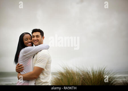 Smiling young couple embracing on a beach. Banque D'Images