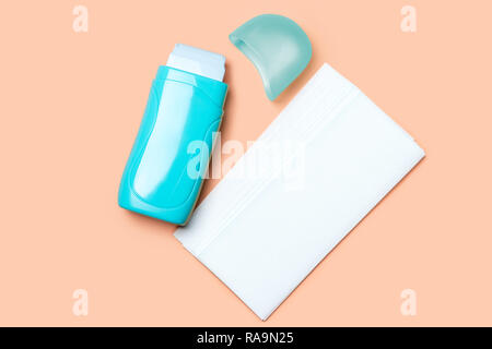 Ouvrez teal roll-on de cire chaude et les bandes de papier sur fond orange Banque D'Images