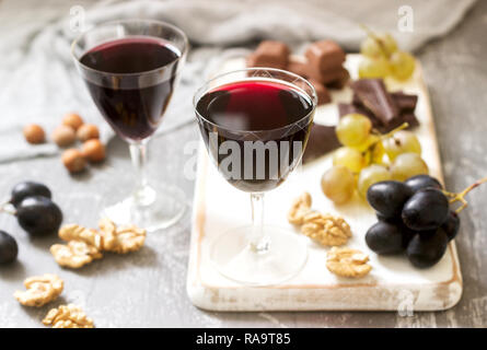 Crème de Cassis liqueur maison servi avec des raisins, noix et chocolat. De style rustique, selective focus. Banque D'Images