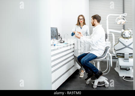 Dentiste avec jeune femme assistante a l'ordinateur dans le cabinet dentaire Banque D'Images