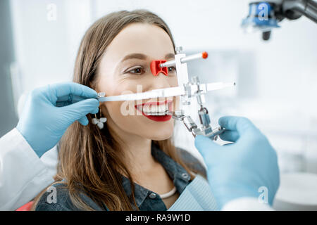 Dentiste de mettre le système de mesure de la mâchoire d'une jeune femme dans le cabinet dentaire du patient Banque D'Images